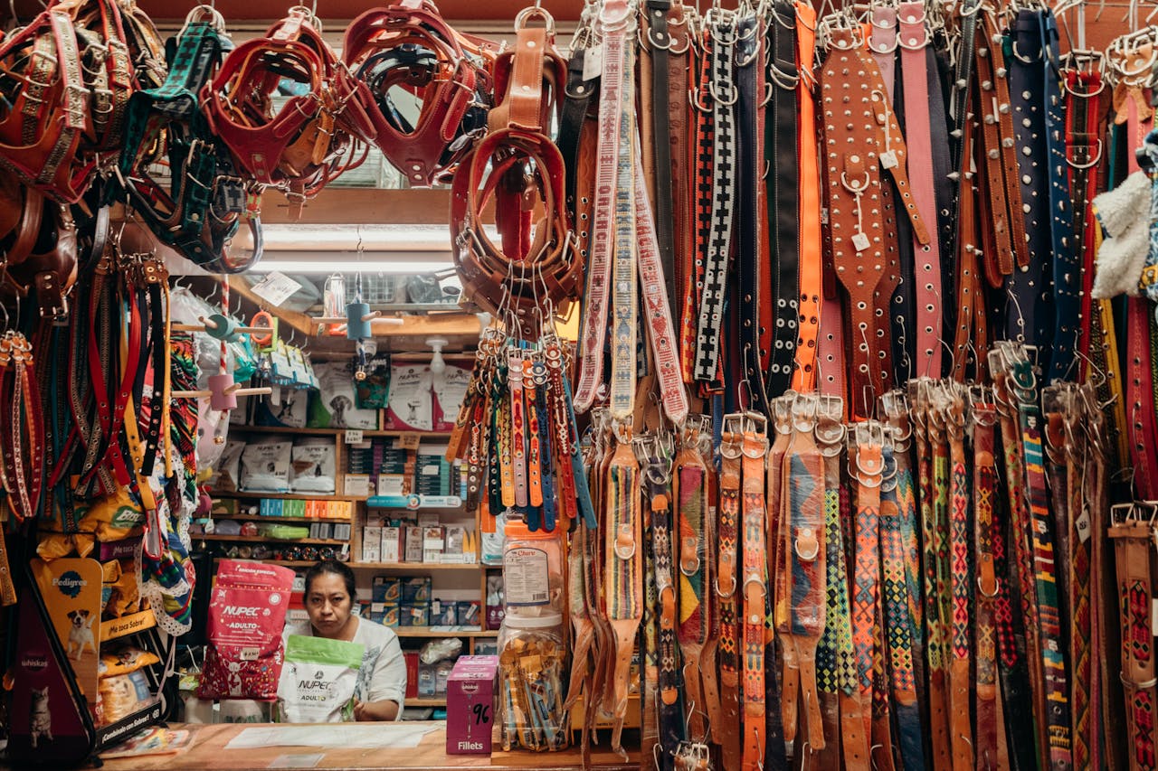 hero-img-01 Colorful leather pet collars at an indoor market stall with a vendor.